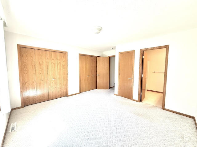 1248 S Hemlock Rd, Hemlock, MI 48626 - unfurnished bedroom featuring two closets, light colored carpet, and connected bathroom