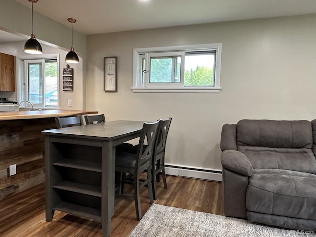 708 Paul Bunyan Ave, Ontonagon, MI 48853 - dining area featuring baseboard heating, dark wood-style flooring, and healthy amount of natural light