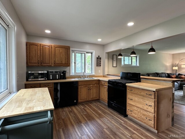 708 Paul Bunyan Ave, Ontonagon, MI 48853 - kitchen with black gas stove, dishwasher, stainless steel microwave, a peninsula, and dark wood-type flooring