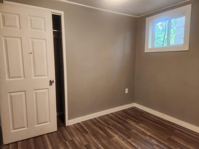 611 Pine St, Harrison, MI 48625 - unfurnished bedroom with dark wood-type flooring