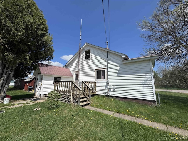 301 Kahma Ave, Amasa, MI 49902 - rear view of property featuring a lawn, a wooden deck, a metal roof, and an outdoor structure