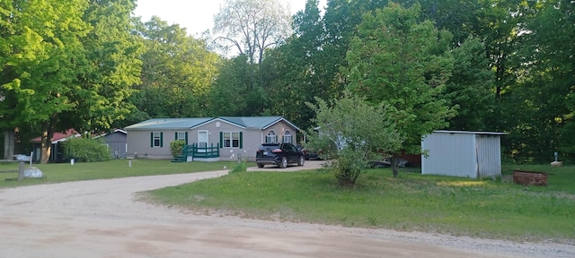 2145 Deer Lake Rd, Harrison, MI 48625 - view of front of house featuring driveway, a front lawn, and a storage unit