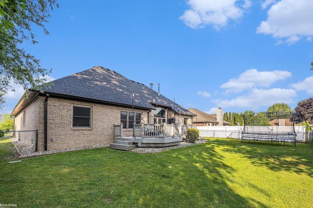 53564 Grace Dr, New Baltimore, MI 48047 - rear view of property with a trampoline, a fenced backyard, a deck, brick siding, and roof with shingles