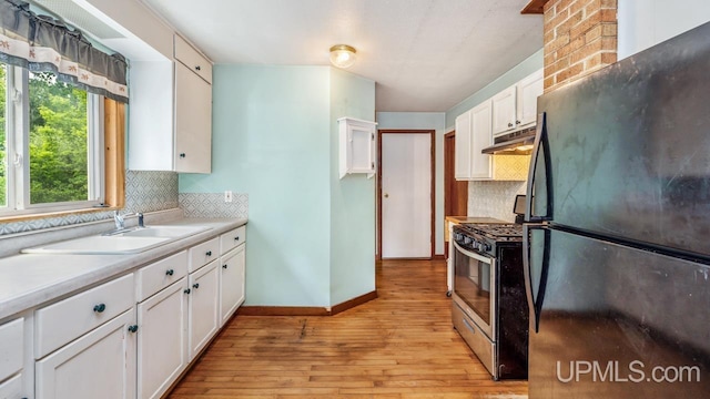 N1953 M67 Hwy, Limestone, MI 49816 - kitchen featuring freestanding refrigerator, stainless steel gas stove, under cabinet range hood, light wood finished floors, and white cabinets