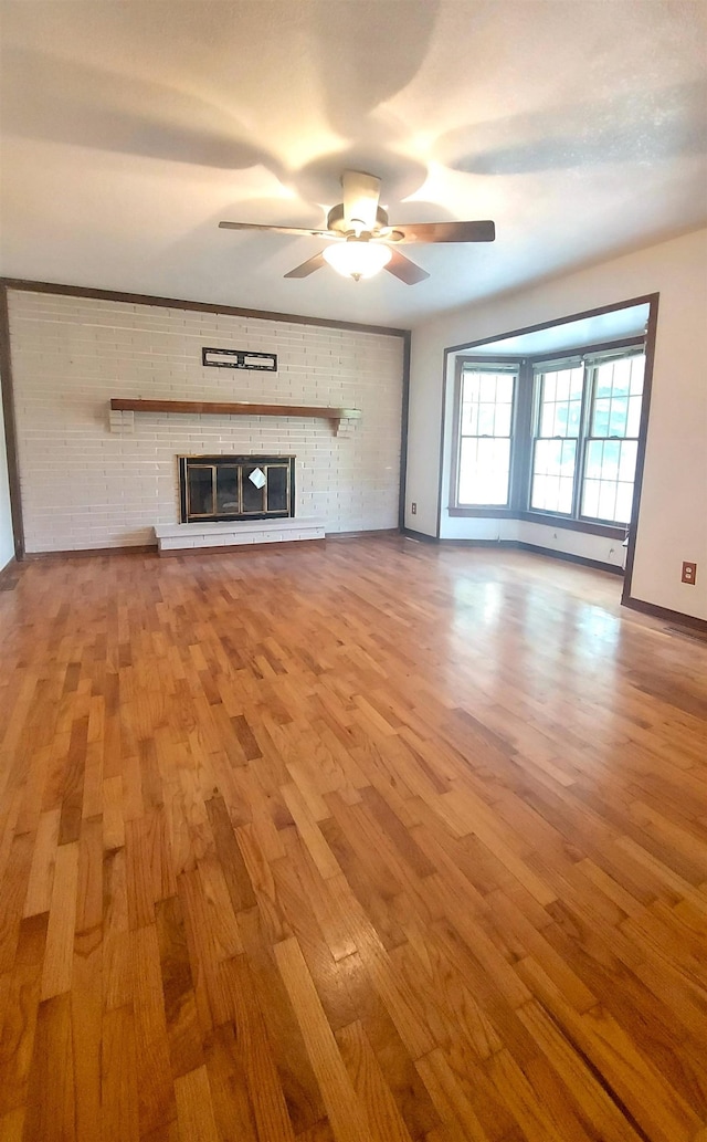 9470 Arbela Rd, Millington, MI 48746 - unfurnished living room with wood finished floors, a ceiling fan, and a fireplace