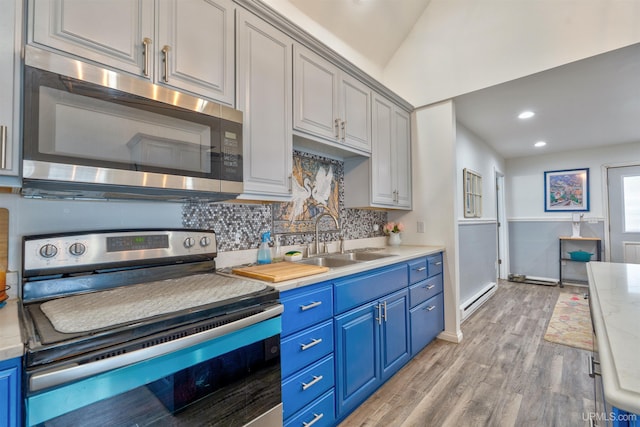 15951 Water St, Garden, MI 49835 - kitchen featuring appliances with stainless steel finishes, blue cabinets, baseboard heating, light wood-style flooring, and backsplash