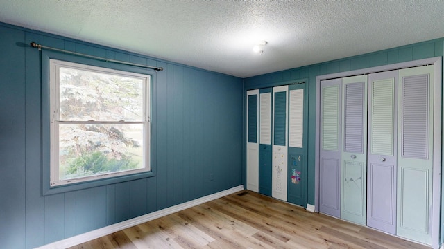13148 Saginaw Rd, Clio, MI 48420 - unfurnished bedroom with multiple closets, light wood-style flooring, and a textured ceiling