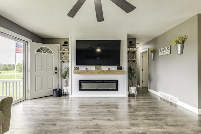 4856 Wagner Rd, Croswell, MI 48422 - unfurnished living room featuring ceiling fan, healthy amount of natural light, wood finished floors, and a large fireplace