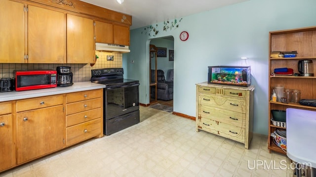 939 N 20th St, Escanaba, MI 49829 - kitchen with black electric range, under cabinet range hood, arched walkways, light floors, and light countertops