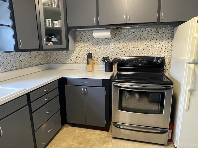 301 N 7th Ave, Hurley, WI 54534 - kitchen with stainless steel electric range, freestanding refrigerator, decorative backsplash, light countertops, and glass insert cabinets