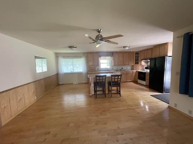 1549 N 7 Mile Rd, Sanford, MI 48657 - kitchen featuring black fridge, white gas stove, plenty of natural light, a breakfast bar area, and wainscoting