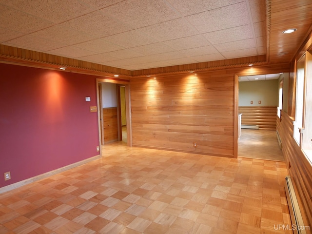1120 Dextrom Rd, Calumet, MI 49913 - empty room with wood walls, baseboard heating, a drop ceiling, and a baseboard heating unit
