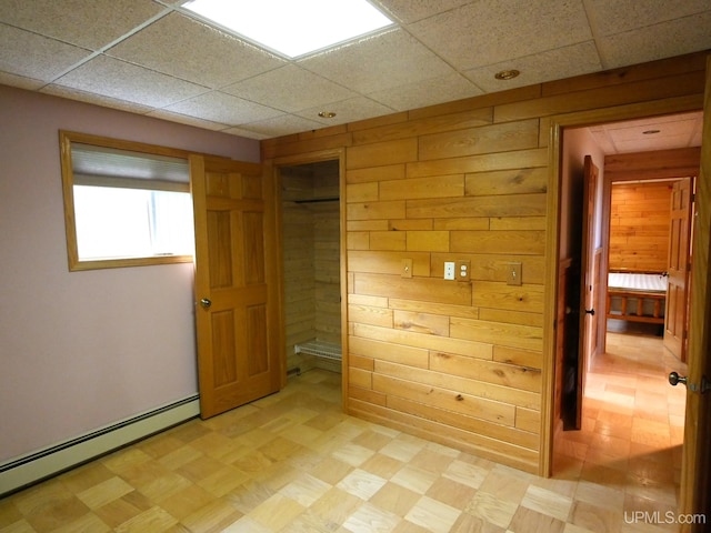 1120 Dextrom Rd, Calumet, MI 49913 - unfurnished bedroom with baseboard heating, light floors, a paneled ceiling, wooden walls, and a closet