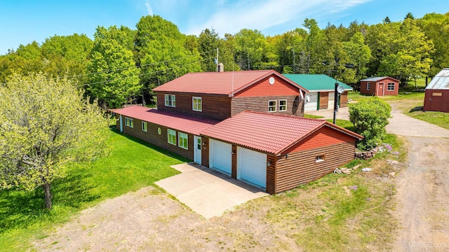 1120 Dextrom Rd, Calumet, MI 49913 - chalet / cabin featuring a storage shed, driveway, a garage, a view of trees, and a front lawn