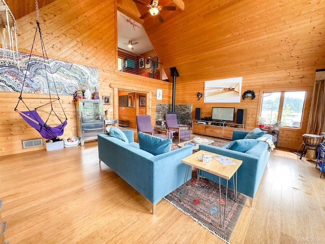 273 N Basin Dr, Negaunee, MI 49866 - living area featuring a wood stove, wooden walls, high vaulted ceiling, wood finished floors, and ceiling fan
