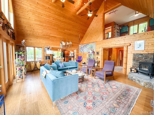 273 N Basin Dr, Negaunee, MI 49866 - living area featuring high vaulted ceiling, wood walls, wood finished floors, a ceiling fan, and a wood stove