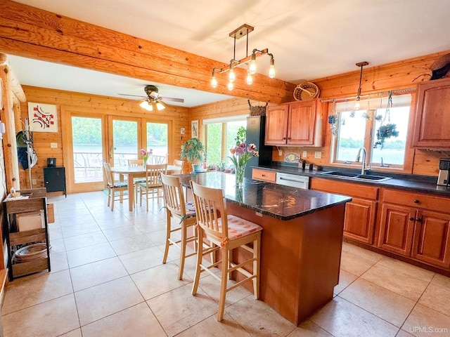 273 N Basin Dr, Negaunee, MI 49866 - kitchen featuring dishwasher, light tile patterned floors, a kitchen breakfast bar, a ceiling fan, and wood walls