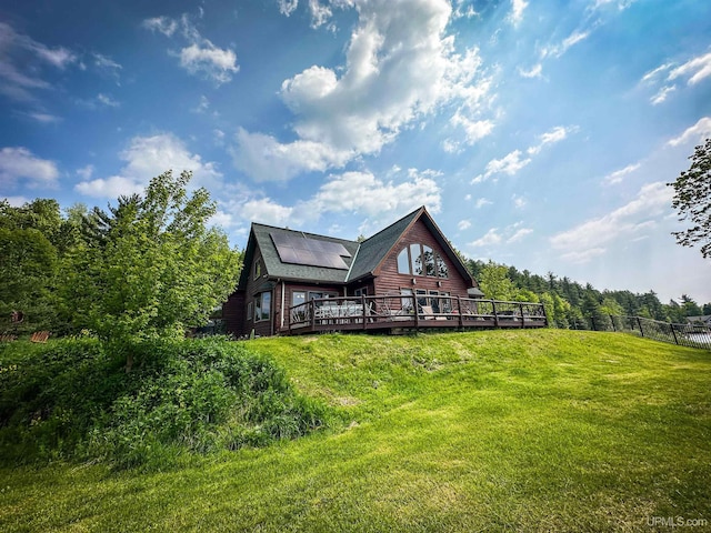 273 N Basin Dr, Negaunee, MI 49866 - rear view of house featuring a wooden deck, roof mounted solar panels, and roof with shingles