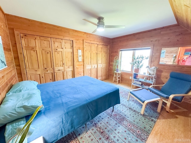 273 N Basin Dr, Negaunee, MI 49866 - bedroom featuring wooden walls, multiple closets, wood finished floors, ceiling fan, and vaulted ceiling