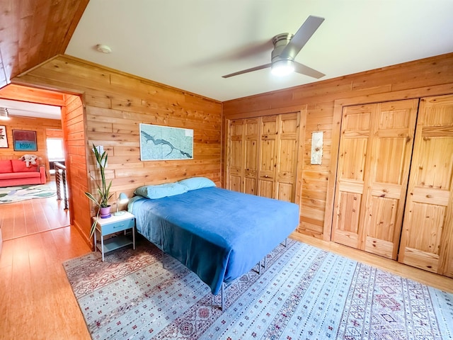 273 N Basin Dr, Negaunee, MI 49866 - bedroom featuring light wood-style floors, wooden walls, two closets, and a ceiling fan