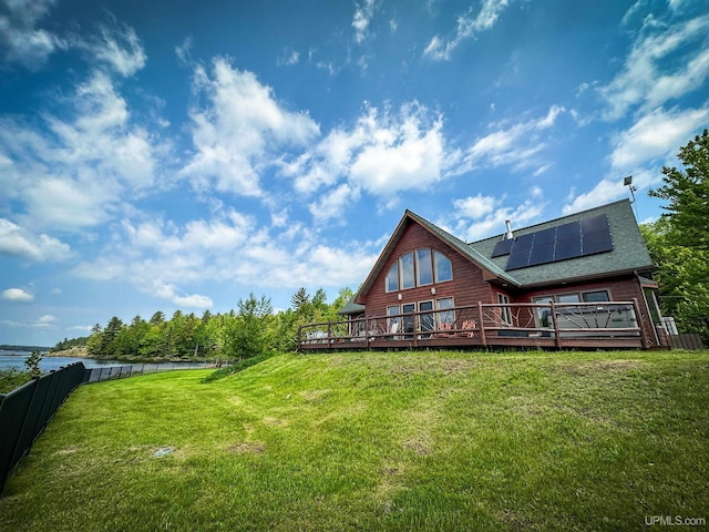 273 N Basin Dr, Negaunee, MI 49866 - back of house featuring roof mounted solar panels, a deck with water view, and a shingled roof