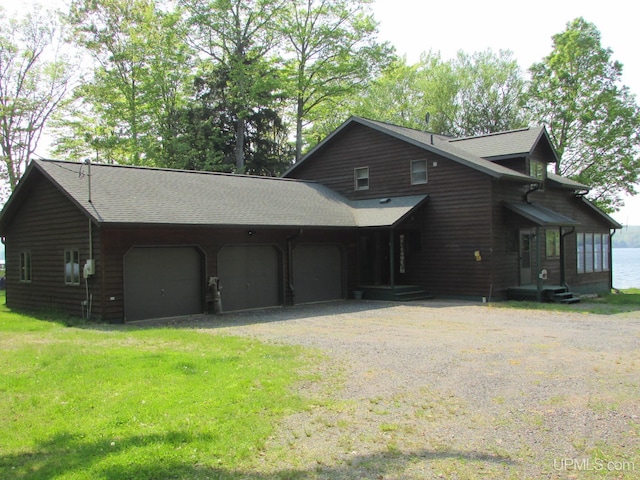 20517 Park Rd, Skanee, MI 49962 - view of front of home featuring dirt driveway, a garage, roof with shingles, and a front lawn