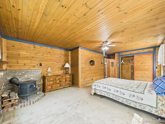 10031 N Ross Lake Rd, Shingleton, MI 49884 - carpeted bedroom featuring a wood stove, wood walls, wooden ceiling, and ceiling fan
