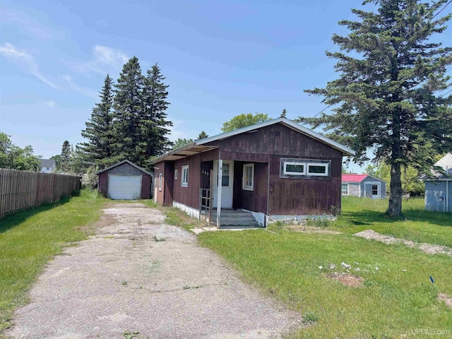 345 N Maple St, Manistique, MI 49854 - bungalow-style home with asphalt driveway, an outdoor structure, a detached garage, and covered porch