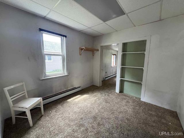 228 Schoolcraft Ave, Manistique, MI 49854 - unfurnished bedroom with a baseboard heating unit, a drop ceiling, a baseboard radiator, and carpet flooring