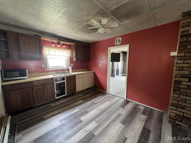 228 Schoolcraft Ave, Manistique, MI 49854 - kitchen with stainless steel microwave, light countertops, a ceiling fan, wood finished floors, and beverage cooler