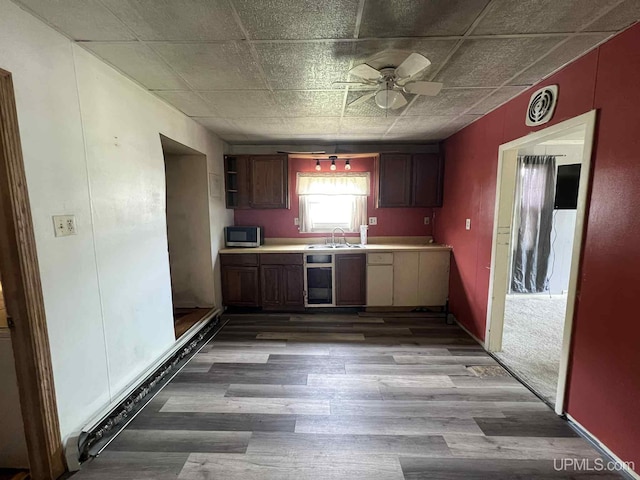 228 Schoolcraft Ave, Manistique, MI 49854 - kitchen with stainless steel microwave, ceiling fan, wood finished floors, and light countertops