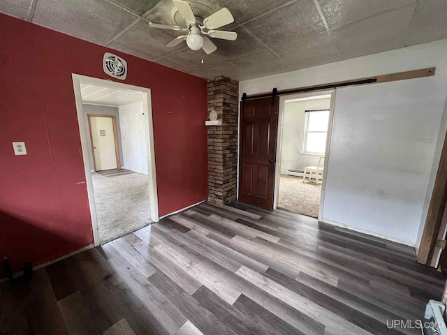228 Schoolcraft Ave, Manistique, MI 49854 - empty room featuring a barn door, baseboard heating, a ceiling fan, and wood finished floors