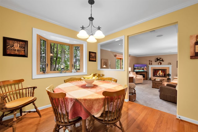 4112 Adams Dr, Shelby Twp, MI 48316 - dining space with a glass covered fireplace, a chandelier, light wood finished floors, and ornamental molding