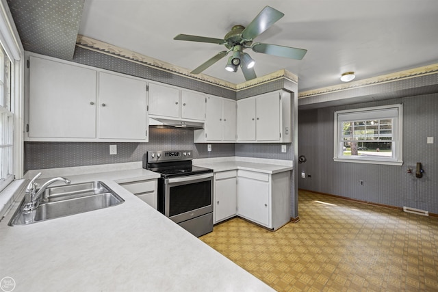 5541 Houghten Dr, Troy, MI 48098 - kitchen featuring stainless steel electric range, wallpapered walls, light countertops, white cabinetry, and under cabinet range hood