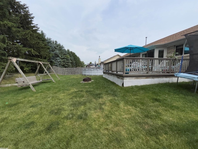51767 Huntley Ave, New Baltimore, MI 48047 - fenced backyard featuring a deck, a fire pit, and a trampoline