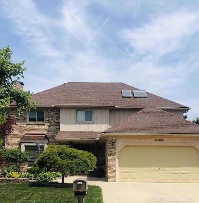 48656 Presidential Dr, Macomb Twp, MI 48044 - view of front of property with a garage, driveway, a shingled roof, brick siding, and a chimney
