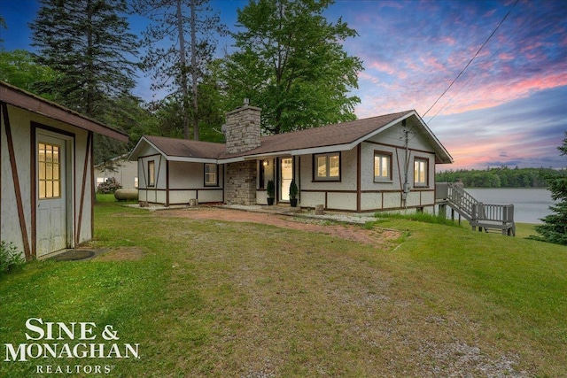2727 Horseshoe Lake Rd, West Branch, MI 48661 - back of property at dusk with a yard, a chimney, and a porch