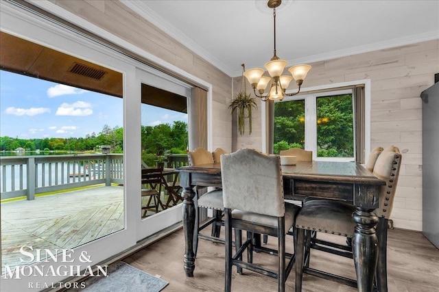 2727 Horseshoe Lake Rd, West Branch, MI 48661 - dining space featuring a water view, ornamental molding, a chandelier, wood finished floors, and wood walls