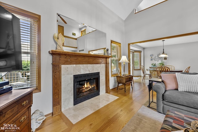 23875 Settlers Dr, Macomb Twp, MI 48042 - living room featuring a tile fireplace, light wood-type flooring, plenty of natural light, and vaulted ceiling