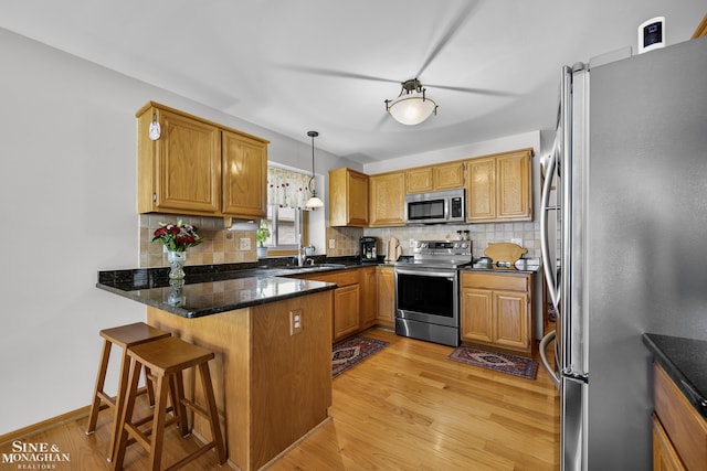 23875 Settlers Dr, Macomb Twp, MI 48042 - kitchen featuring appliances with stainless steel finishes, a peninsula, backsplash, and light wood-style floors