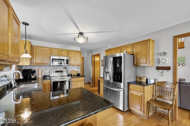 23875 Settlers Dr, Macomb Twp, MI 48042 - kitchen with stainless steel appliances, backsplash, light wood-style flooring, hanging light fixtures, and dark stone countertops