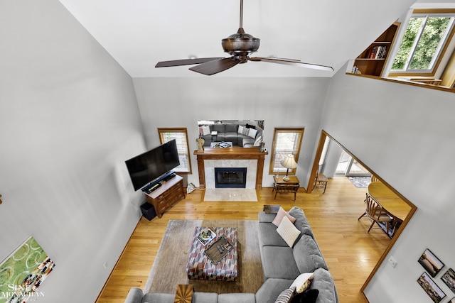 23875 Settlers Dr, Macomb Twp, MI 48042 - living area featuring wood finished floors, a ceiling fan, a tile fireplace, and a high ceiling
