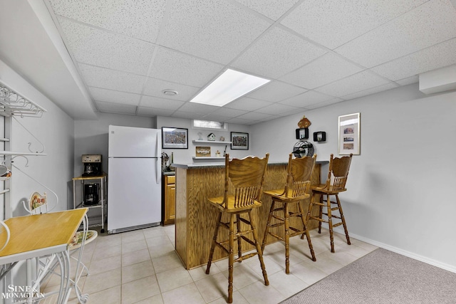 23875 Settlers Dr, Macomb Twp, MI 48042 - kitchen with freestanding refrigerator, a paneled ceiling, a kitchen breakfast bar, a peninsula, and brown cabinets