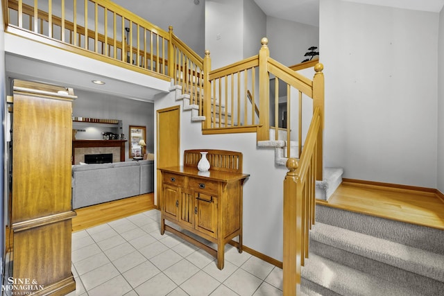 23875 Settlers Dr, Macomb Twp, MI 48042 - stairs featuring high vaulted ceiling, tile patterned flooring, and a fireplace