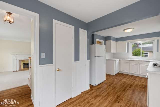 1284 Brys Dr, Grosse Pointe Woods, MI 48236 - kitchen featuring white appliances, light wood finished floors, white cabinetry, light countertops, and a high end fireplace
