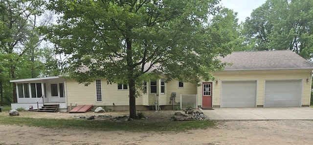 10505 N Athey Ave, Harrison, MI 48625 - view of front of home featuring a garage, concrete driveway, entry steps, and a sunroom