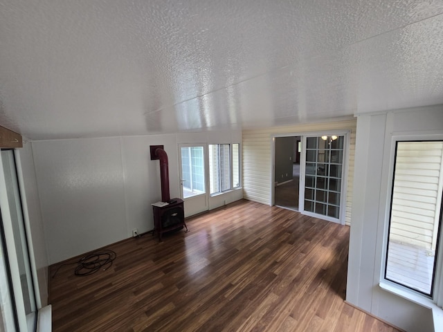 10505 N Athey Ave, Harrison, MI 48625 - unfurnished living room featuring a wood stove, wood finished floors, and a textured ceiling