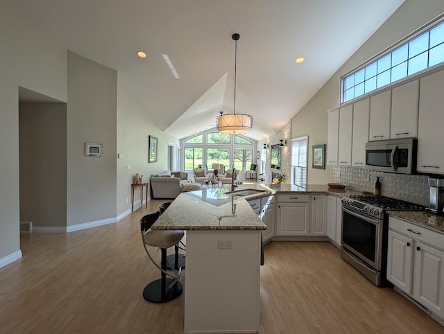 5953 Qwinn Ct, Bay City, MI 48706 - kitchen with stainless steel appliances, a peninsula, open floor plan, high vaulted ceiling, and light wood-style floors