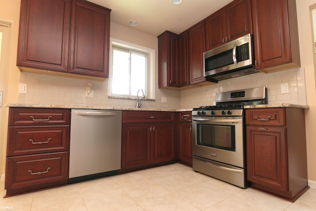 31717 Tecla St, Warren, MI 48088 - kitchen with stainless steel appliances, backsplash, light stone counters, and reddish brown cabinets