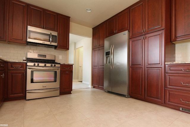 31717 Tecla St, Warren, MI 48088 - kitchen featuring appliances with stainless steel finishes, reddish brown cabinets, backsplash, light stone countertops, and recessed lighting